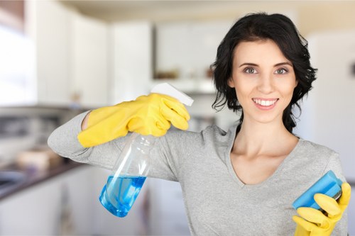 Office cleaner sanitising shared workspace surfaces